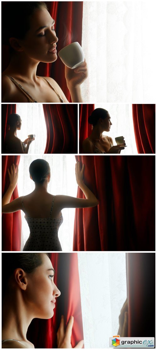 Woman with a cup of coffee by the window - Stock Photo